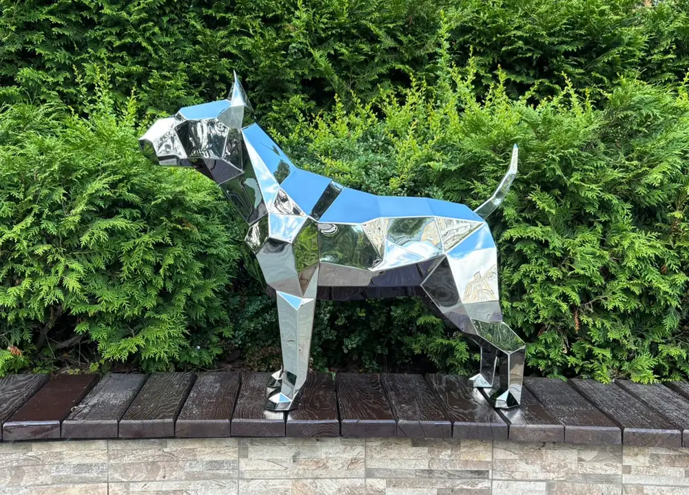 Mirror-polished stainless steel low-poly dog sculpture outdoors