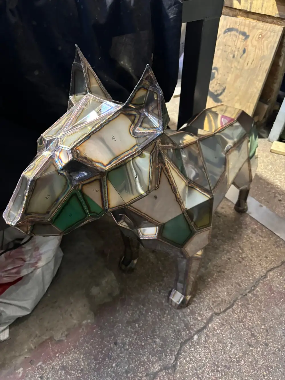 Stainless steel low-poly bull terrier sculpture before polishing, raw welded surface