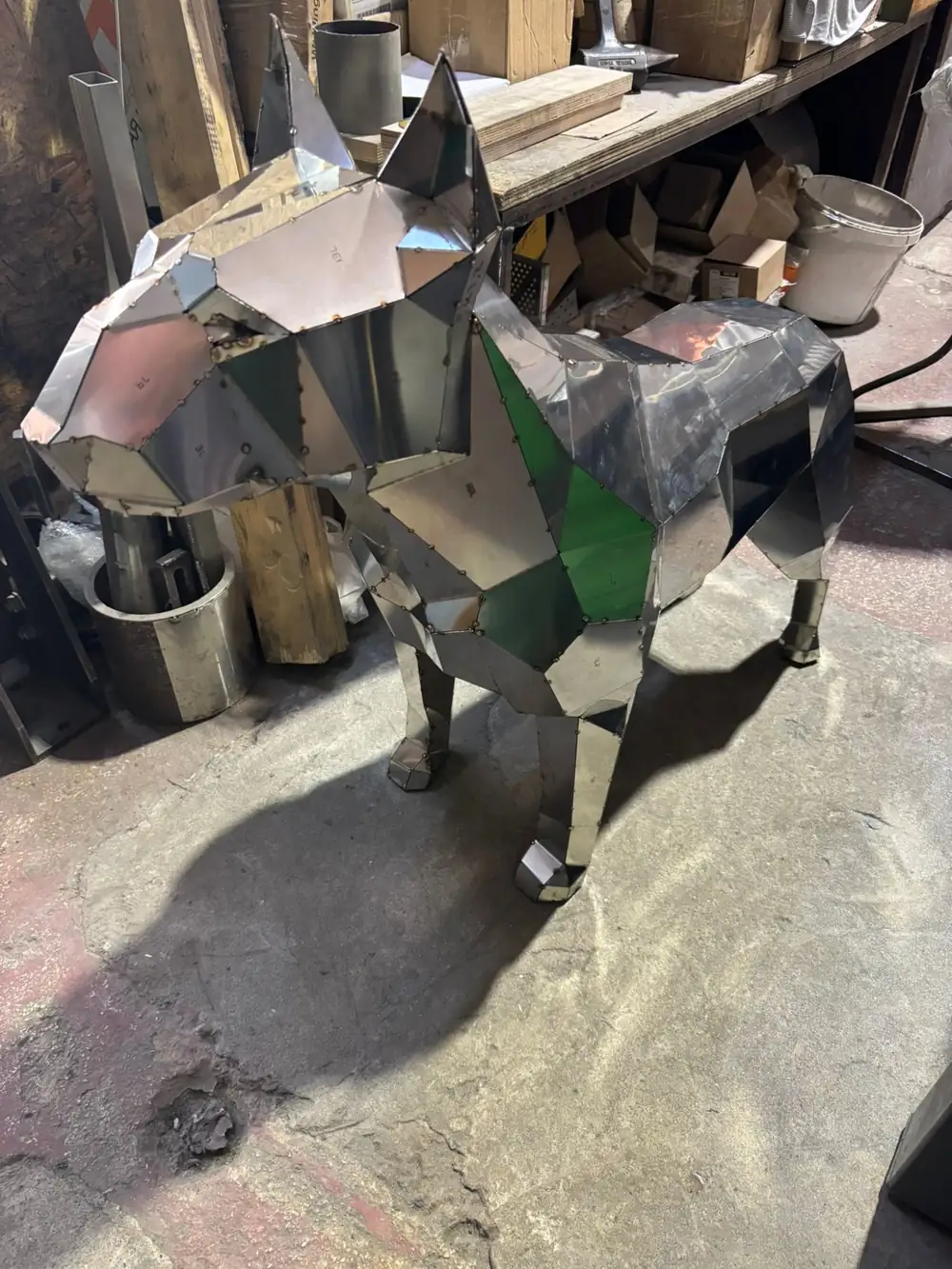 Low-poly steel bull terrier tacked together from numbered panels in a workshop
